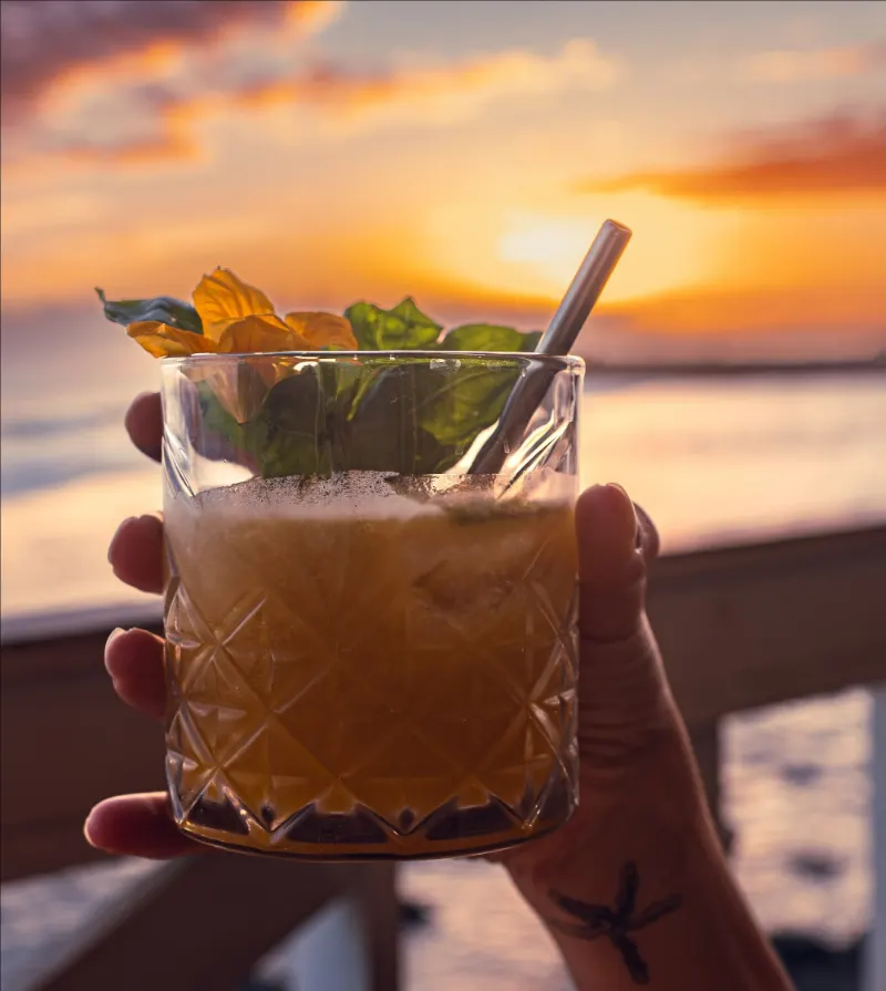 Un cocktail tenu face au coucher du soleil, sur la terrasse