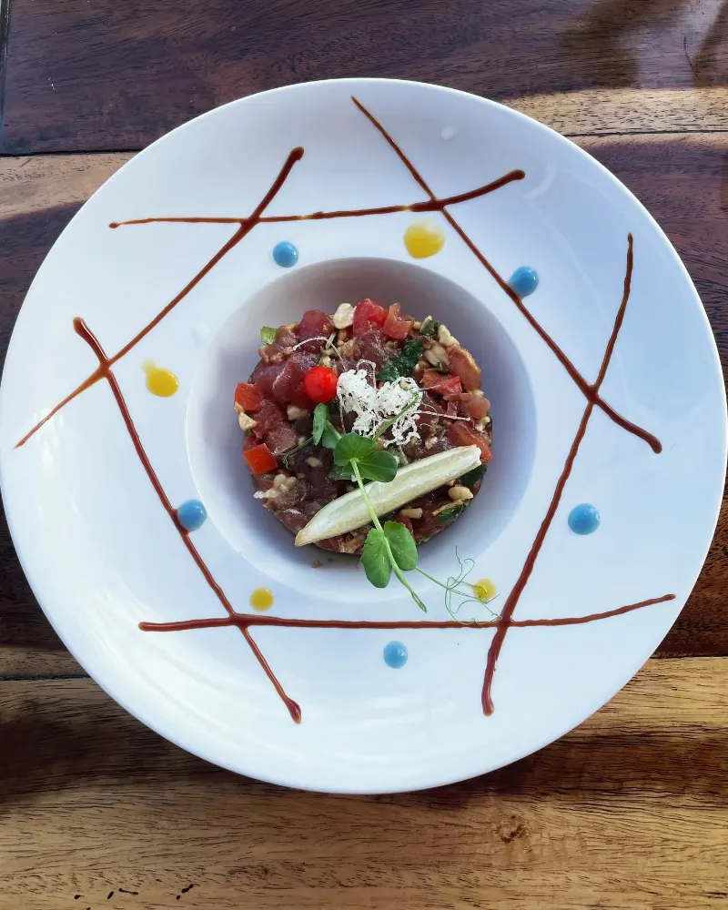 Un tartare dressé dans une assiette blanche, avec un décor de sauce